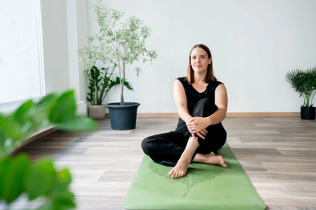 Regina sitzt auf einer Yogamatte im AXIS Studio